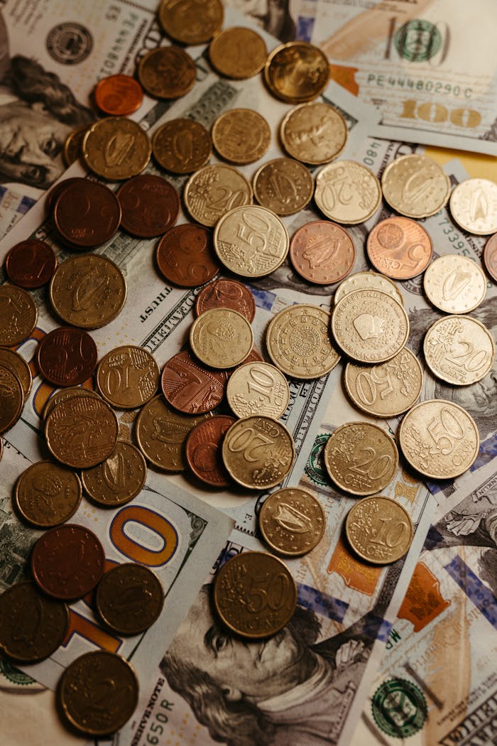 A detailed image of coins scattered over US dollar bills, showcasing currency diversity.