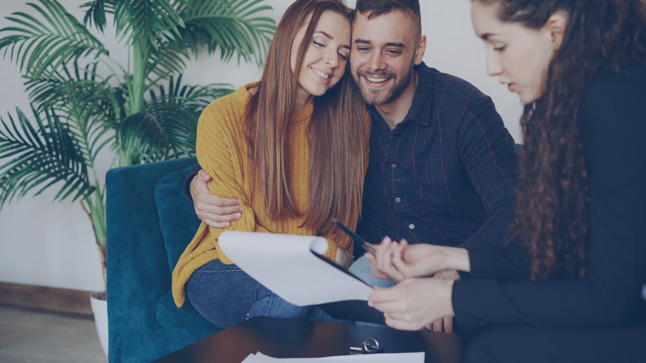 Smiling couple consulting with an adviser in a cozy office setting.